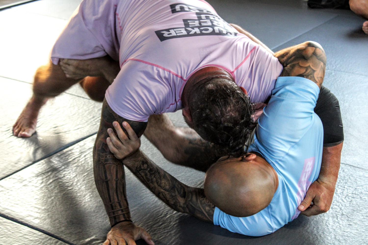 Coach Weiss training with his Black Belt student, Chuck. They're both outfitted in Sucker Free apparel and are actively engaged in a roll. 