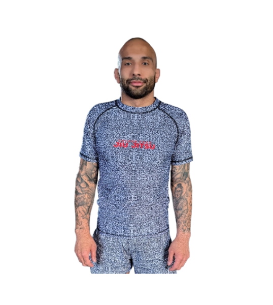 Coach Weiss standing in his custom-made Snow Leopard nogi rashguard with the red retro SFJJ logo. His tattoos of his Afghan heritage are visible.